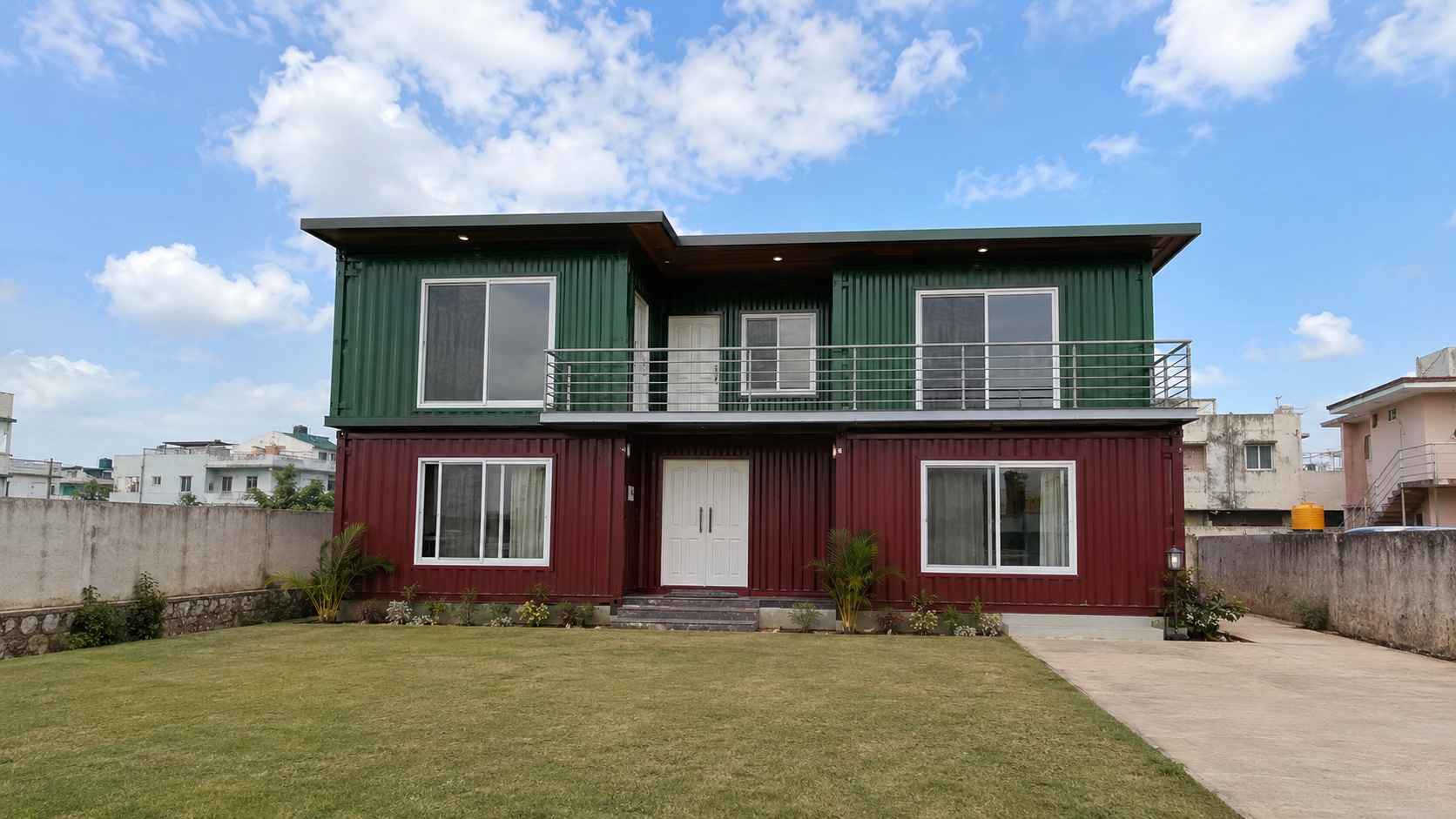 SAMAN 2,200 sq ft affordable container home installed on a private residential plot in India — two-storey Burgundy Red and Forest Green exterior