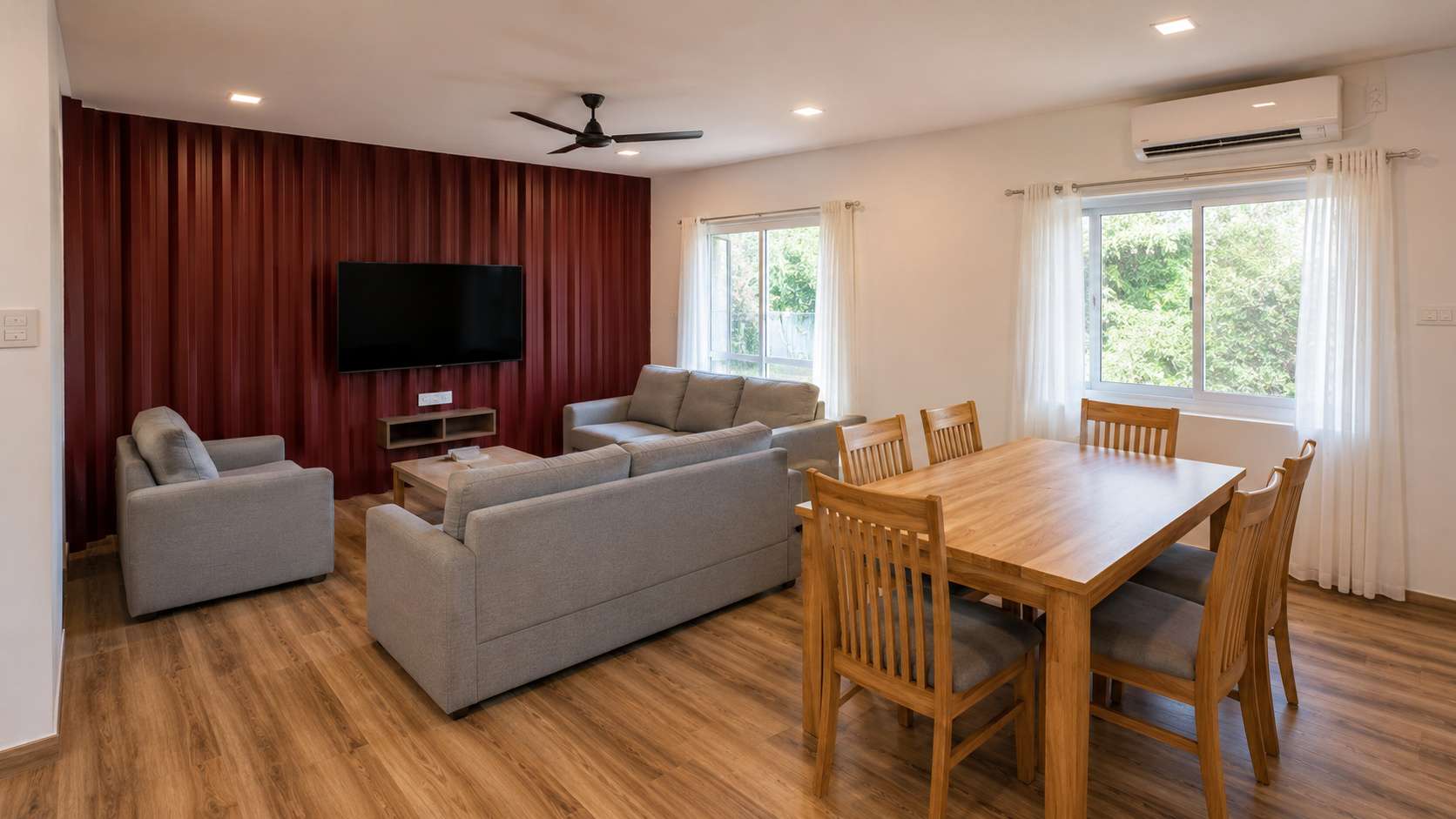 Living-dining room interior of SAMAN affordable container home with vinyl plank flooring, split AC, and Burgundy Red accent wall panel