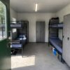 Inside a 20×20 ft bunkhouse cabin with double-deck bunk beds and lockers for a small crew.