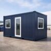 Navy blue cargo container office exterior with white-framed door, two windows, corrugated wall panels, and durable modular office design