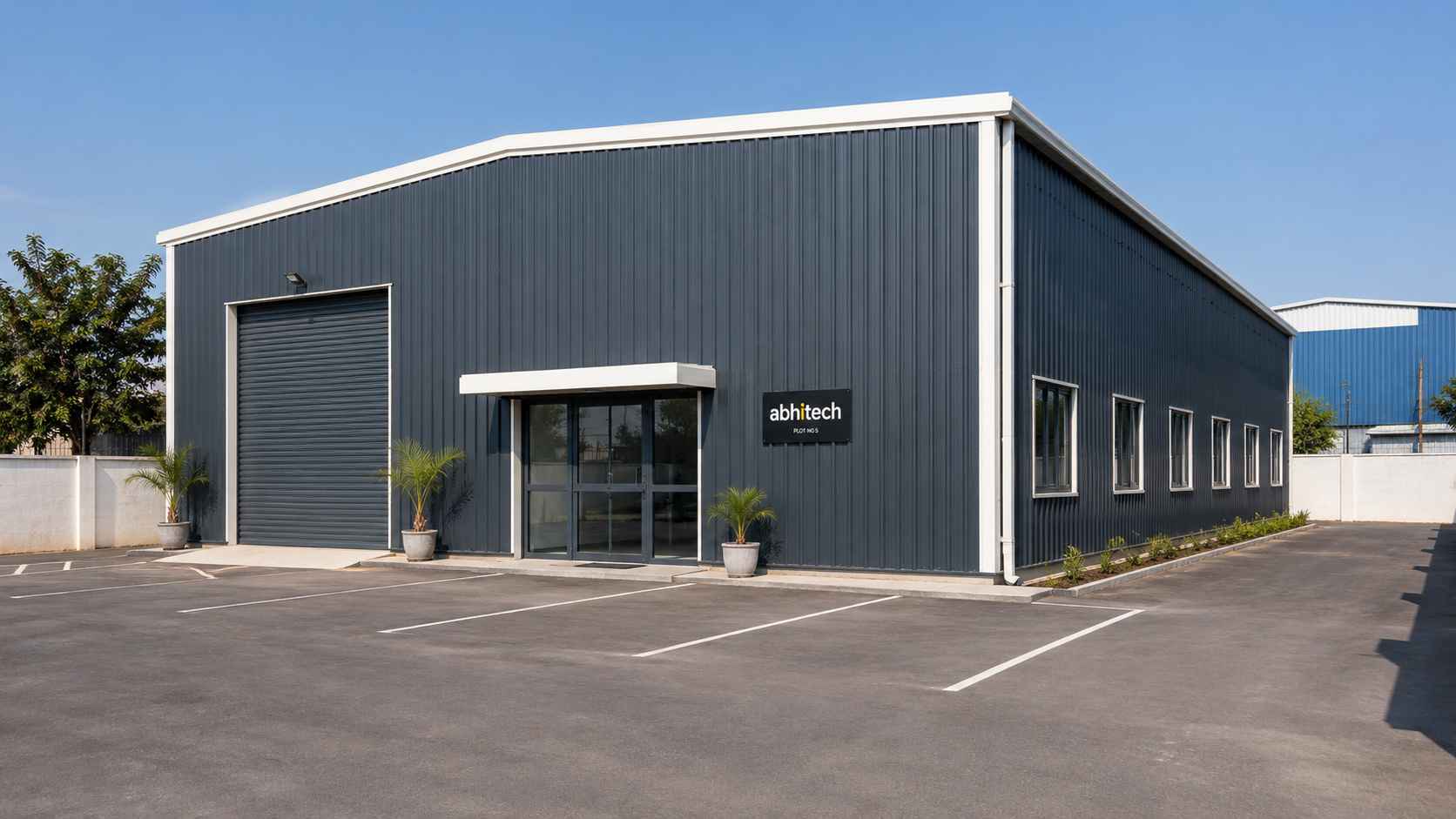 Charcoal-grey 60 by 36 foot commercial shed with glazed entry and parking on an Indian commercial plot.