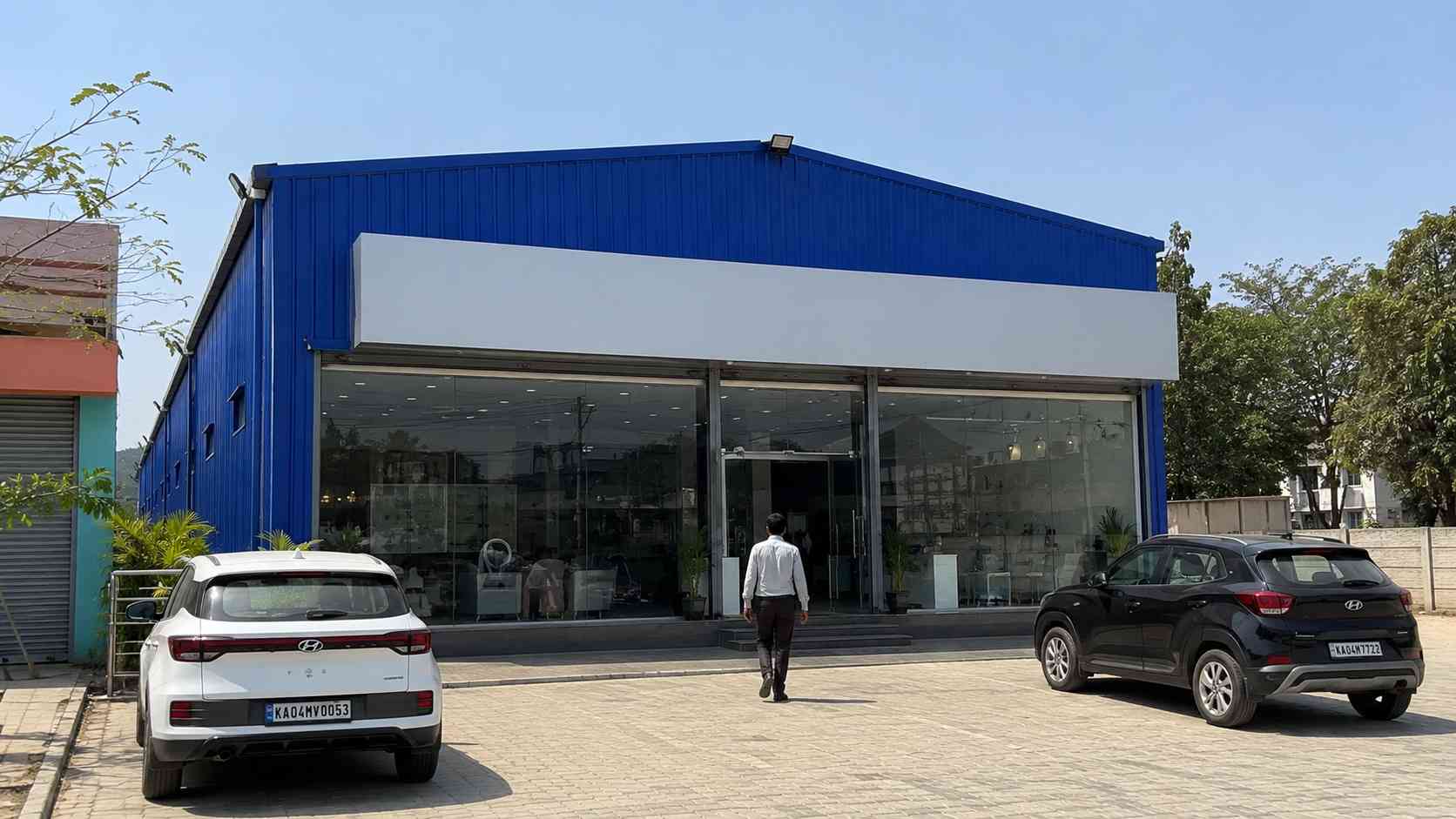 Royal-cobalt-blue commercial shed used as a showroom with a glazed shopfront and customer parking in India.