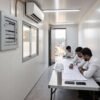 Portable construction site office interior with engineers reviewing project blueprints inside a modular container office cabin