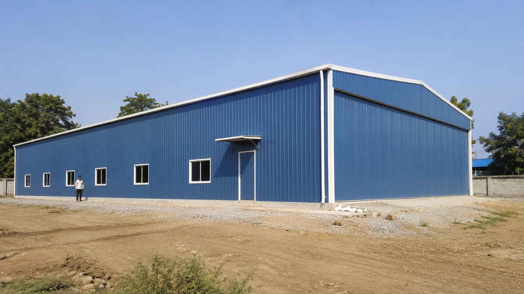 Single-storey 90×30 ft steel-blue prefabricated building completed on a concrete plinth.