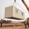 Prefabricated portable office container being installed with crane at a construction site
