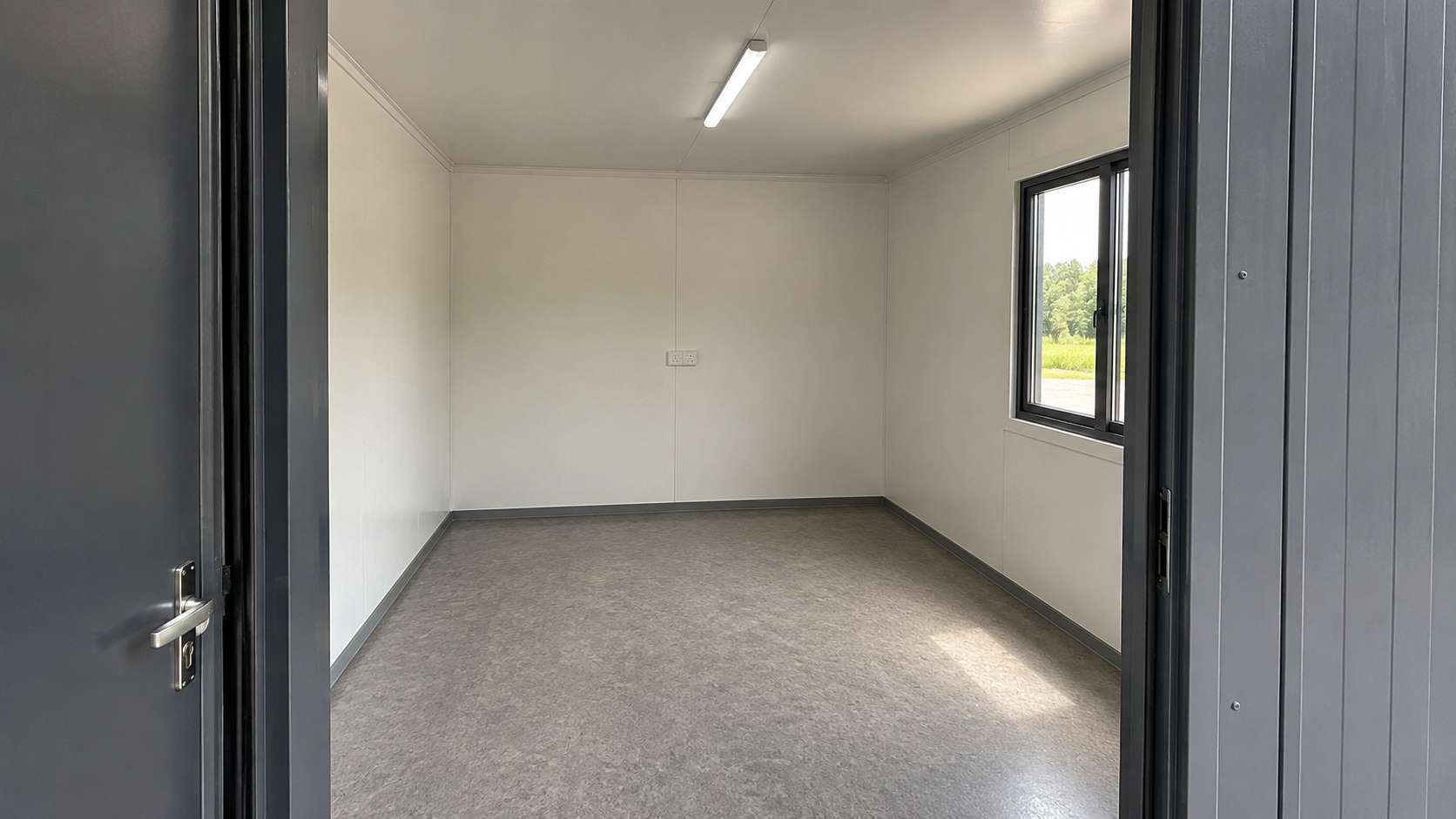 Inside a container building showing white MD-board lining, vinyl floor and wall switchboard.