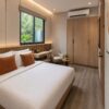 Boutique container hotel cottage room interior with queen bed, built-in wardrobe, writing nook, and window-side reading seat in a 20-foot module