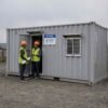 Front view of container site office with entry door and four corner foundation pads visible.