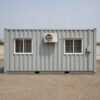 Container site office in three-quarter front view with main door and electrical box visible.