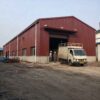 Burgundy-red engineered building in use with a truck at the open shutter and workers nearby.