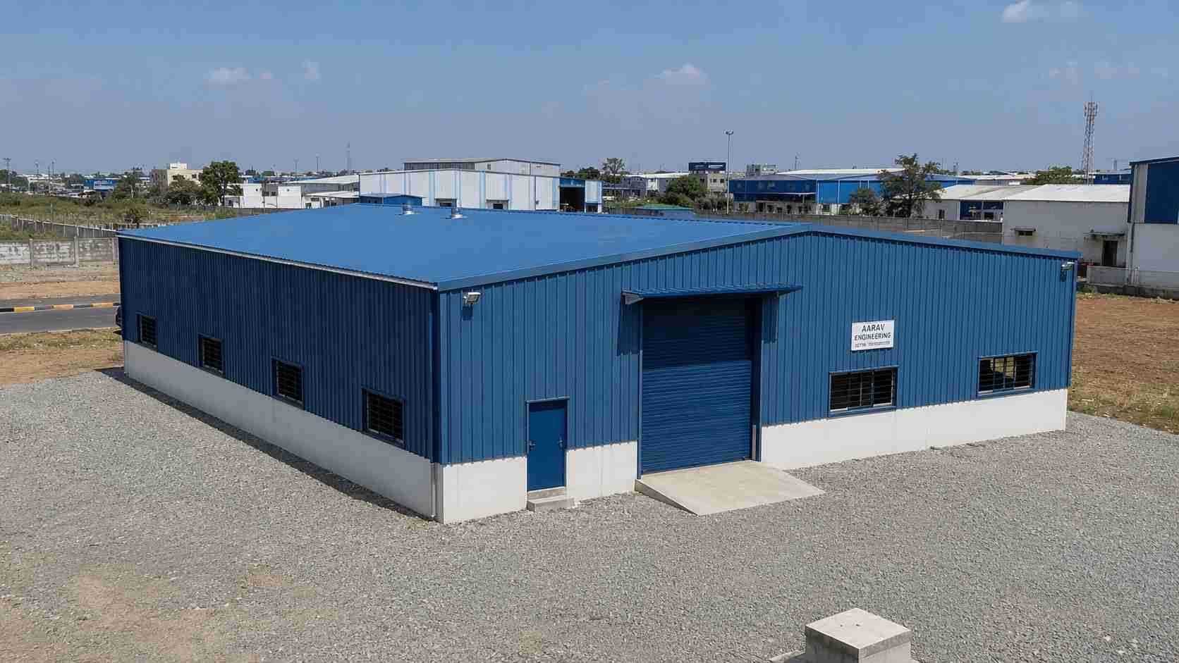 Steel-blue engineered building on a plot in an Indian industrial park.