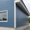 Close-up of steel-blue PUF-panel wall, eave flashing and plinth on an engineered building.