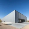 Silver engineered metal building with a wide open entrance bay on a concrete apron