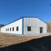 White and blue engineered metal building showing the long side elevation with a window row