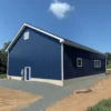 Navy engineered metal building gable end with a personnel door and external electrical box