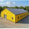 Yellow engineered steel building with dark gable roof and a long row of side-wall windows