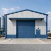 Front view of a blue engineered steel structure with a central roller-shutter loading bay