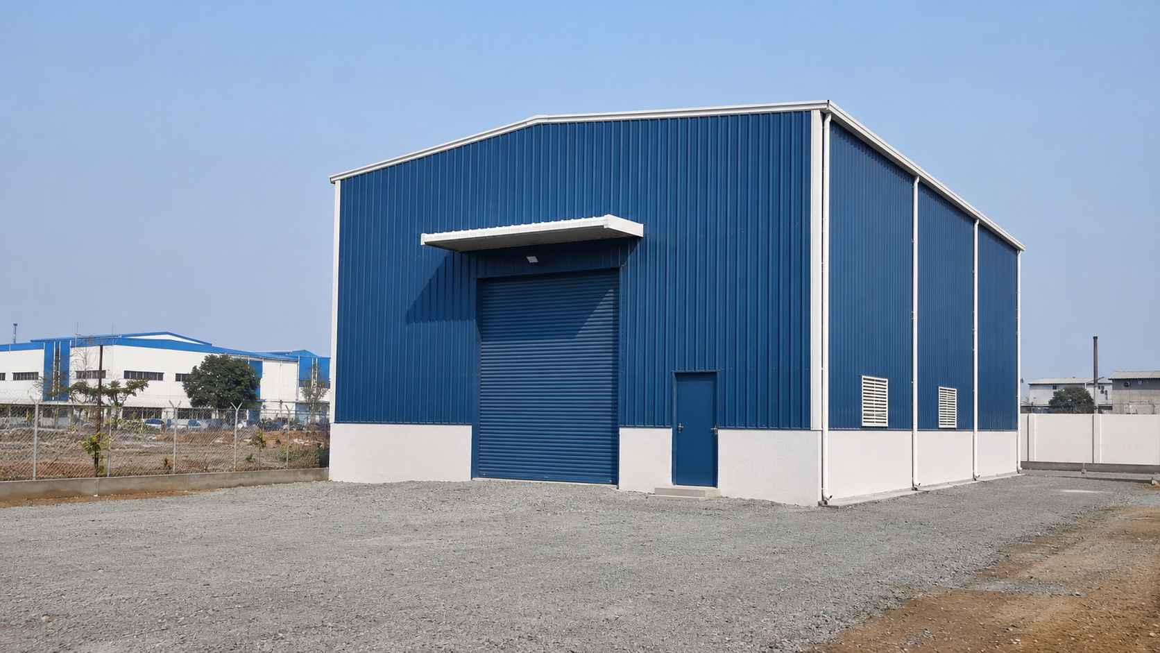 Blue engineered steel structure standing on a prepared plot at an Indian industrial estate