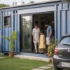 Indian family at the doorway of their steel-blue shipping container home in evening light