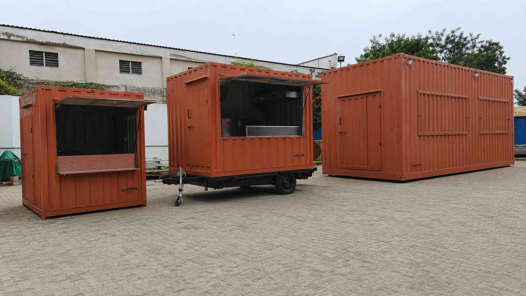 Three SAMAN container cafe builds parked in a row — 10×10 cafe body, 15×8 food truck container on trailer wheels, and 22×12 mobile restaurant.