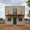 Front view of inexpensive container home with Forest Green door and Warm Taupe balcony railing on prepared plinth.