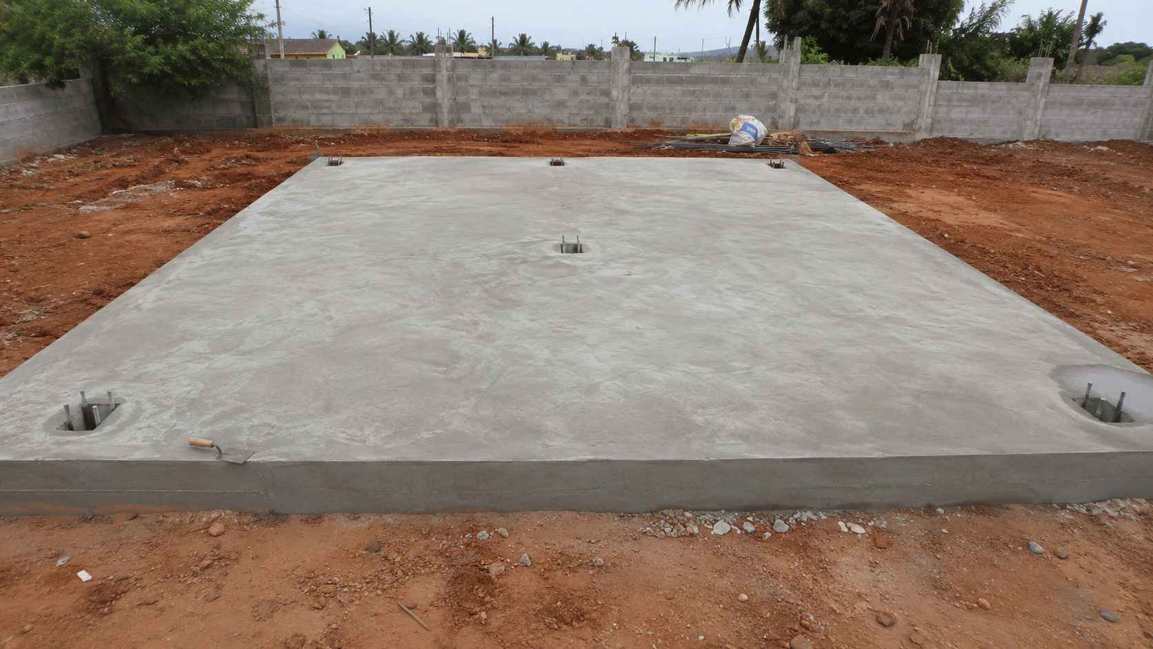 Freshly finished 42×36 ft RCC plinth foundation on a cleared rural plot, prepared for inexpensive container home placement.