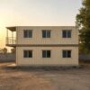 Full side elevation of two-storey container home showing 40-ft length and balcony in golden-hour light.