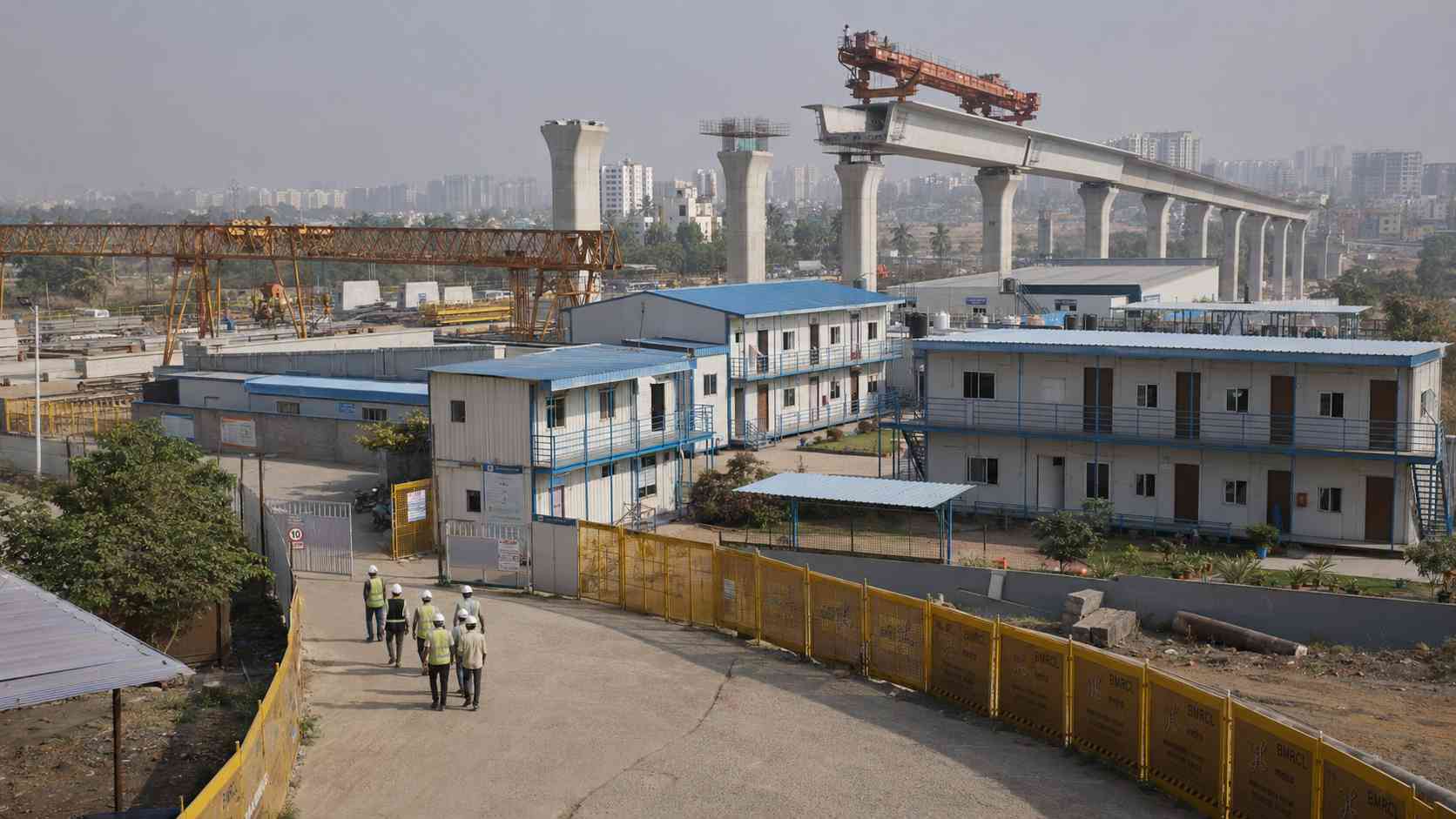 Labor accommodation supporting a metro rail construction project on the outskirts of an Indian metropolitan city with elevated viaduct visible in the background.
