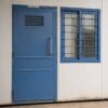 Close-up of a labor accommodation dormitory door, window with MS grille, and PUF sandwich panel wall joint.