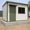 Sage Industrial labor hutment door with weather hood and reinforced concrete plinth foundation.