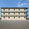 Front elevation of a SAMAN labor shelter block showing the regular grid of 24 rooms across three floors