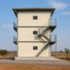 Side profile of a SAMAN G+2 labor shelter block showing the external staircase and walkway