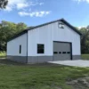 White and grey metal building with garage roller door installed on a grassed site