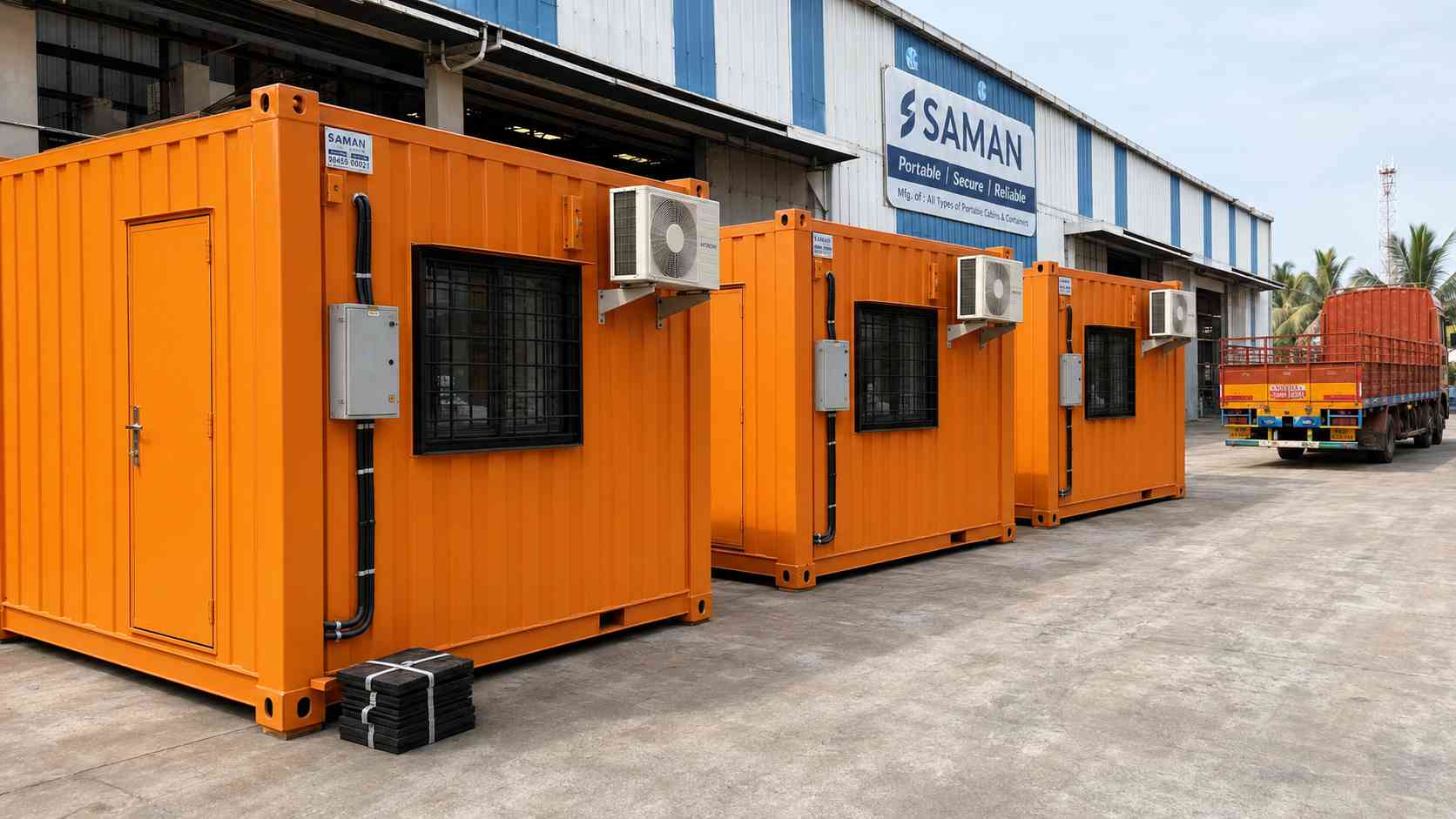 Three safety orange SAMAN mobile container offices ready for Pan India dispatch from a Bangalore factory yard.
