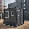 Black mobile toilet with door and window at an Indian construction site