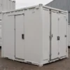 White mobile toilet cabin with two lockable doors on a level yard, front-angle view.