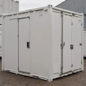 White mobile toilet cabin with two lockable doors on a level yard, front-angle view.