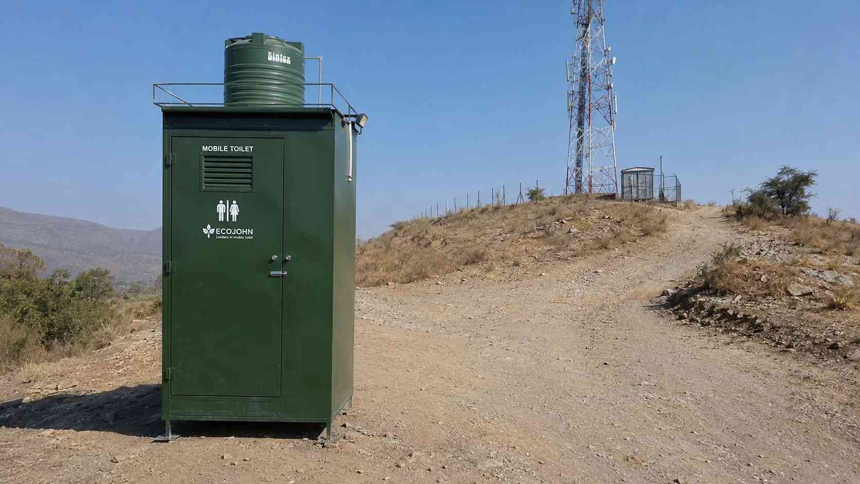 Green mobile toilet at a remote telecom tower base on open ground
