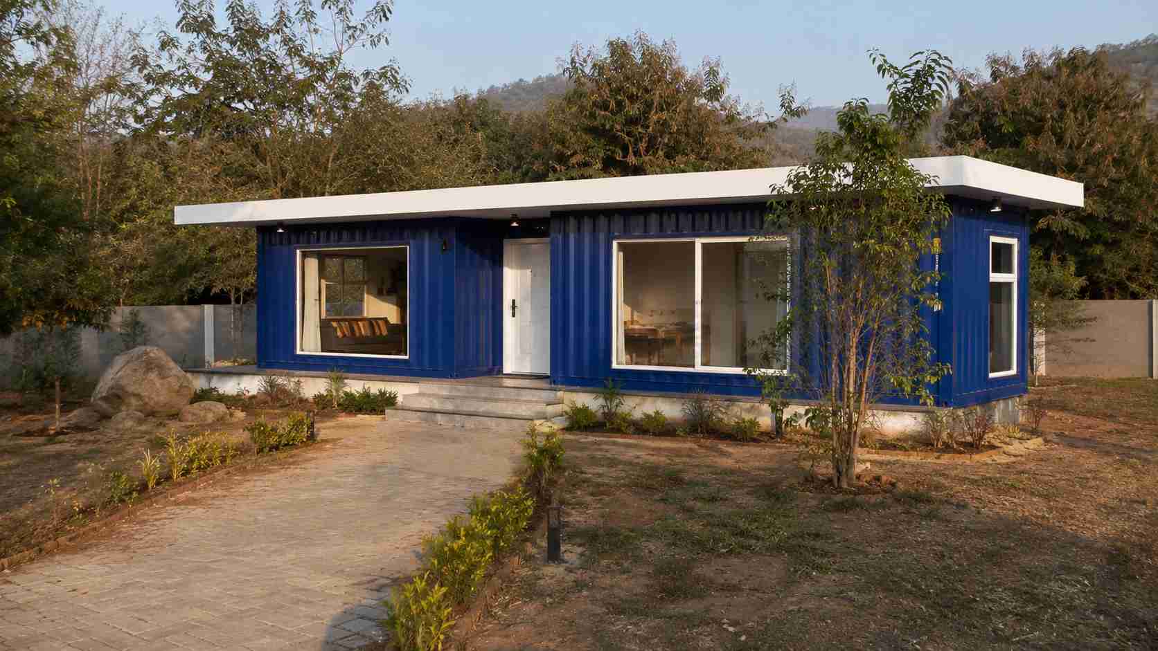 Royal cobalt blue modern container home with clean lines on a landscaped Indian residential plot.