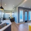 Open-plan kitchen and living area inside a modern container home with blue accent wall and wood floor.
