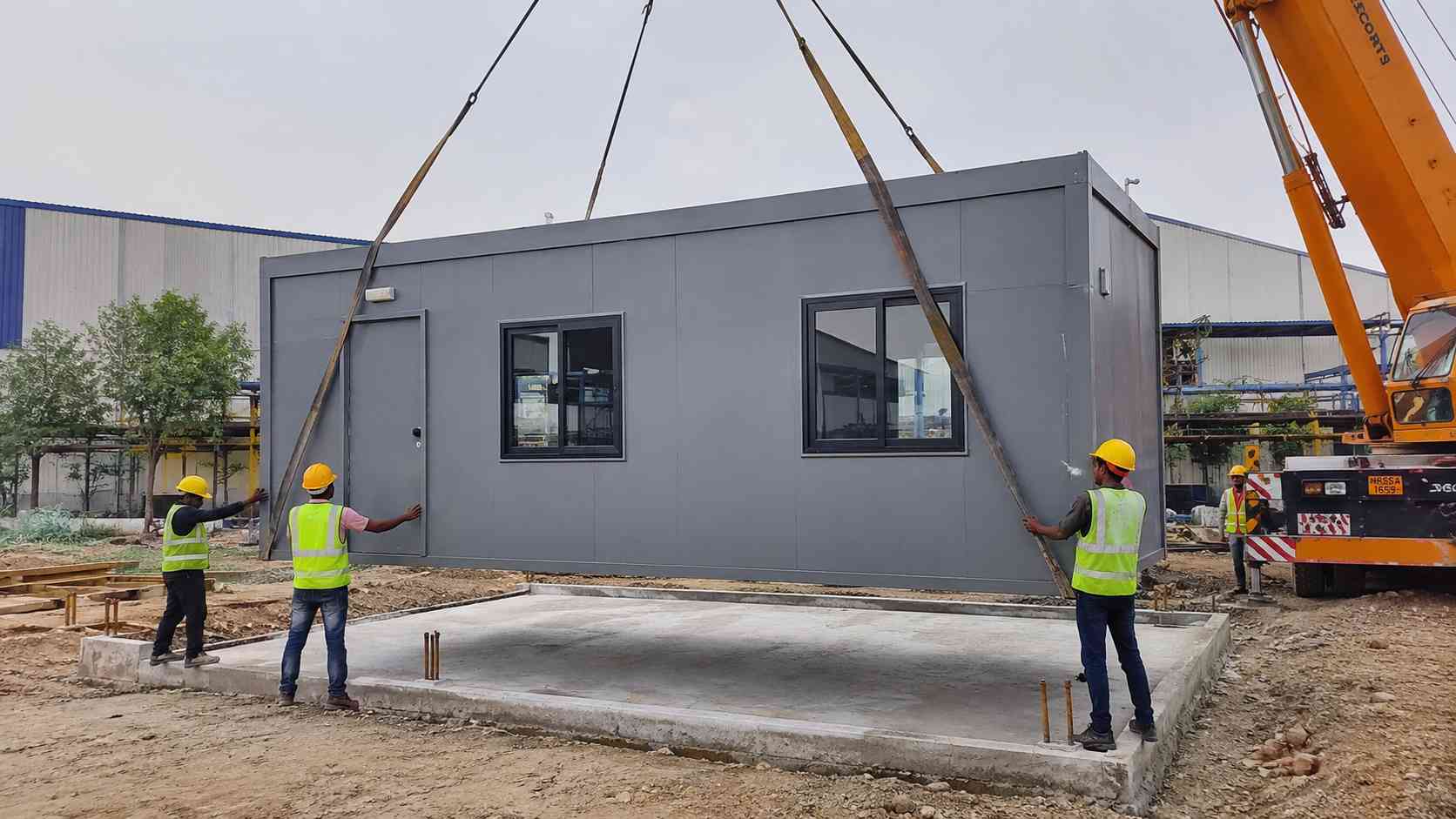 Steel Grey modular office building module craned onto a prepared base at a commercial site.