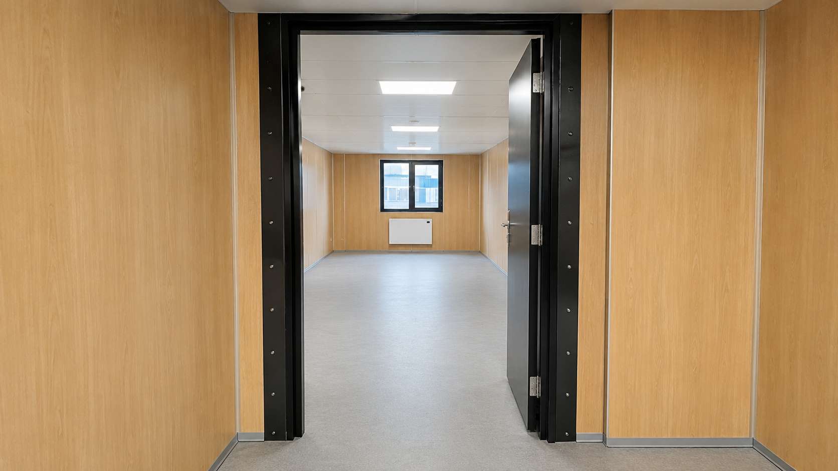 Interior doorway connecting two modular portable office modules showing level vinyl floor and bolted steel frame join