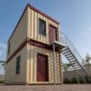 Worm's eye view of a 2-level stacked container office complex at a government water-resources project headquarters, sand-beige with maroon-red accents.