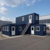 L-shape stacked container office complex at a logistics warehousing campus, deep navy blue with white window frames.