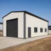 Off-white 60×30 ft PEB steel building with charcoal roof and roller-shutter door on a levelled Indian industrial plot