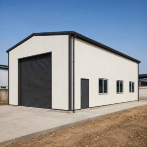 Off-white 60×30 ft PEB steel building with charcoal roof and roller-shutter door on a levelled Indian industrial plot