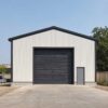 Gable end of a 30 ft wide PEB steel building with a charcoal roller-shutter door and side personnel door