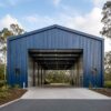 Navy-blue PEB steel structure gable end with an open drive-through clear-span bay.