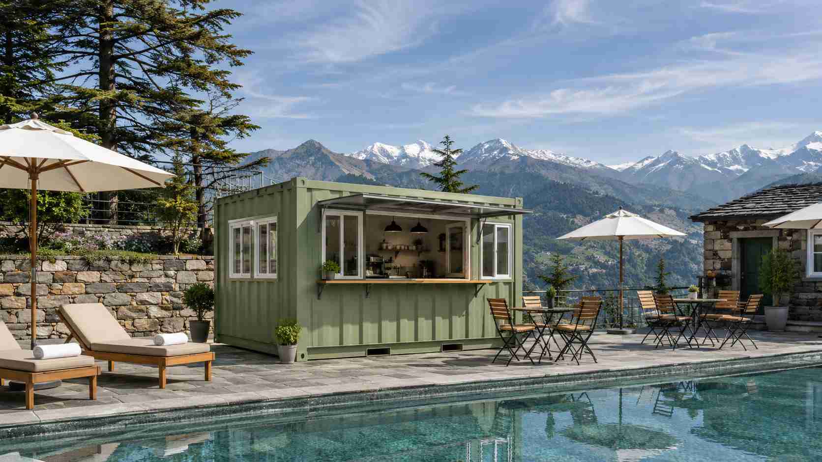 Sage green pop-up restaurant container as a pool-deck cafe at a Manali hill-station resort with Himalayan peaks in background