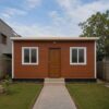 Brick terracotta porta cabin house shown straight-on from the front with door and two windows.